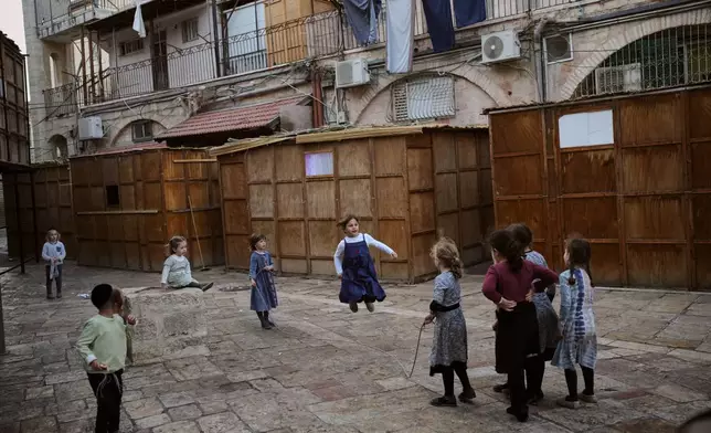 Ultra-Orthodox Jewish children play next to Sukkahs, a temporary structures built for the upcoming Jewish holiday of Sukkot in the Orthodox Jewish neighborhood of Mea Shearim in Jerusalem, Sunday, Oct. 5, 2025. (AP Photo/Ohad Zwigenberg)