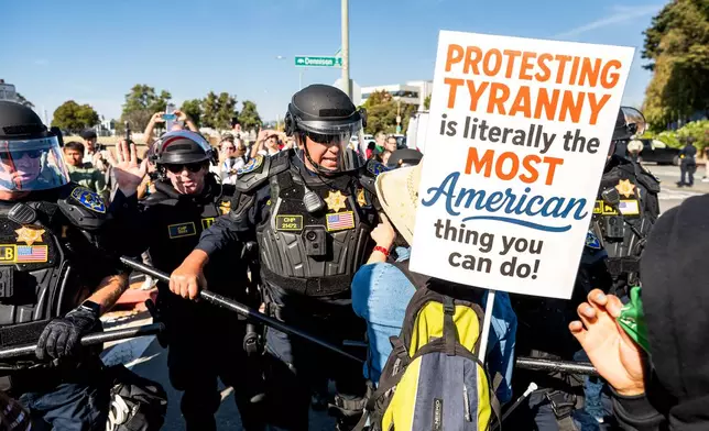 California Highway Patrol officers move back protesters who were blocking the entrance to Coast Guard Base Alameda on Thursday, Oct. 23, 2025, in Oakland, Calif. (AP Photo/Noah Berger)