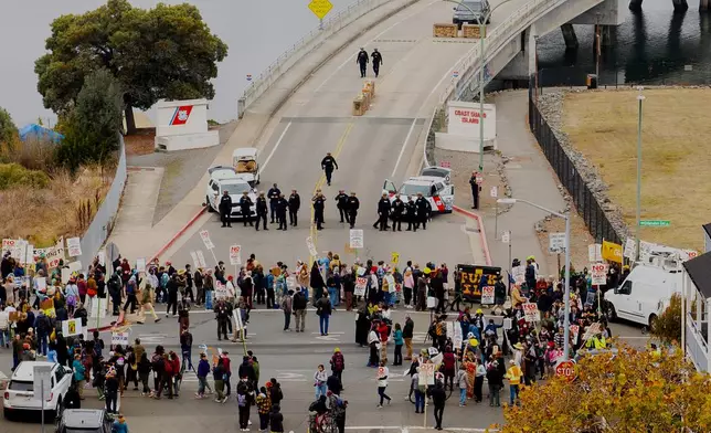 EDS NOTE: OBSCENITY - Protesters block the entrance to Coast Guard Base Alameda shortly after a caravan of U.S. Customs and Border Protection personnel arrived on Thursday, Oct. 23, 2025, in Oakland, Calif. (AP Photo/Noah Berger)