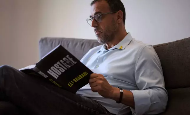 Eli Sharabi, who was abducted during the cross-border attack on Israel on Oct. 7, 2023, and held hostage by Hamas for 16 months, poses with his new book "Hostage" for a photo in Herzliya, Israel, Thursday, September 18, 2025. (AP Photo/Ariel Schalit)