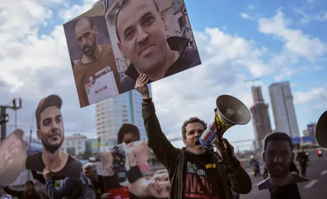 FILE - A demonstrator wave photos of freed Israeli hostage Eli Sharabi before and after his captivity blocks a highway during a protest demanding all hostages release from Hamas captivity, in Tel Aviv, Israel, Thursday, Feb. 13, 2025. (AP Photo/Oded Balilty, File)