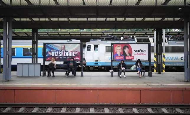 People sit by election posters ahead of Parliamentary elections in Prague, Czech Republic, Sept. 26, 2025. (AP Photo/Petr David Josek)