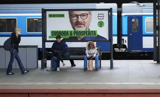 People sit by election posters ahead of Parliamentary elections in Prague, Czech Republic, Sept. 26, 2025. (AP Photo/Petr David Josek)