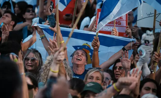People react as they gather to watch a live broadcast of Israeli hostages released from Gaza at a plaza known as hostages square in Tel Aviv, Israel, Monday, Oct. 13, 2025. (AP Photo/Emilio Morenatti)