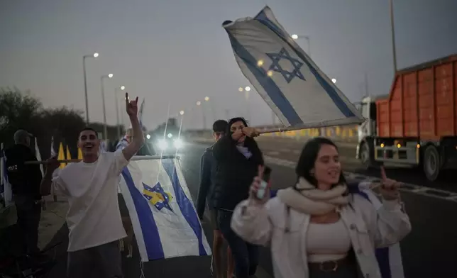 People hold Israeli flags as they gather prior to the release of Israeli hostages held in Gaza, in front of a military base near Reim Area, southern Israel, on Monday, Oct, 13, 2025. (AP Photo/Leo Correa)