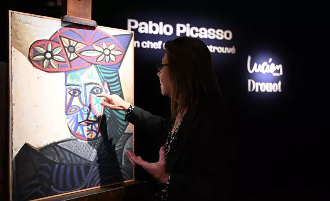 Art expert Agnes Sevestre-Barbe points to a rediscovered Picasso painting "Bust of a Woman in a Flowery Hat", Wednesday, Oct. 22, 2025 in Paris. The portrait painted in 1943 will be sold at auction Friday in Paris, was bought in 1944 and shows his partner Dora Maar. (AP Photo/Emma Da Silva)