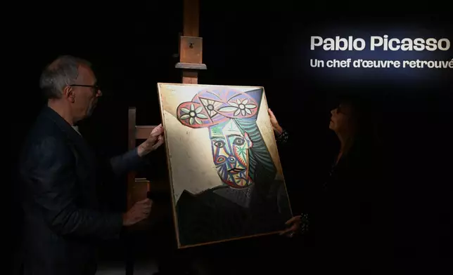 Art expert Agnes Sevestre-Barbe, right, and auction officer Christophe Lucien, stand by a rediscovered Picasso painting "Bust of a Woman in a Flowery Hat", Wednesday, Oct. 22, 2025 in Paris. The portrait painted in 1943 will be sold at auction Friday in Paris, was bought in 1944 and shows his partner Dora Maar. (AP Photo/Emma Da Silva)