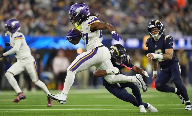 Minnesota Vikings running back Jordan Mason (27) runs with the football as Los Angeles Chargers cornerback Tarheeb Still (29) tries to tackle during the second half of an NFL football game Thursday, Oct. 23, 2025, in Inglewood, Calif. (AP Photo/Gregory Bull)