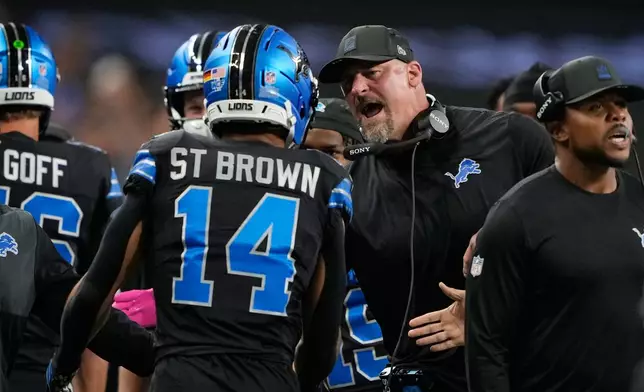 Detroit Lions head coach Dan Campbell, center, congratulates wide receiver Amon-Ra St. Brown (14) after his touchdown during the first half of an NFL football game against the Tampa Bay Buccaneers, Monday, Oct. 20, 2025, in Detroit. AP Photo/Ryan Sun)