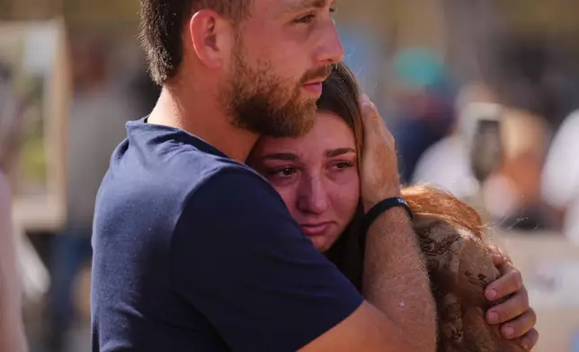 People embrace during a memorial marking two years anniversary of the Oct. 7, 2023 deadly Hamas attack on Israel, at the site of the Nova music festival near Kibbutz Reim in southern Israel, where hundreds of revelers were killed and abducted in the assault, Tuesday, Oct. 7, 2025. (AP Photo/Ariel Schalit)