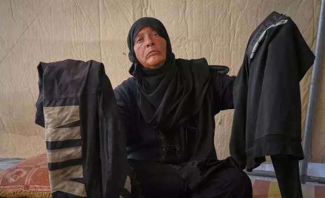 Fadwa al-Ghalban holds clothes belonging to her son, Mosaab, at her tent in Muwasi, along Gaza's southern coast, Oct. 3, 2025. Fadwa has had no word from Mosaab since July, when his cousins last saw him near their house as an Israeli strike destroyed it in the southern town of Maan. (AP Photo/Jehad Alshrafi)