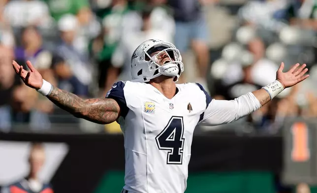 Dallas Cowboys' Dak Prescott reacts to a touchdown run by Javonte Williams during the first half of an NFL football game against the New York Jets Sunday, Oct. 5, 2025, in East Rutherford, N.J. (AP Photo/Adam Hunger)