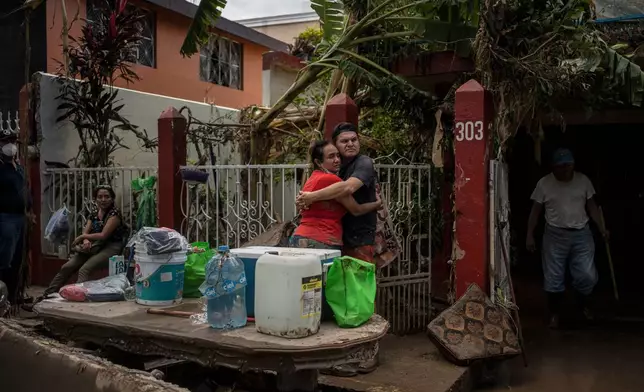 Locals embrace outside a flooded house in Poza Rica, Mexico, Sunday, Oct. 12, 2025, after widespread flooding and landslides. (AP Photo/Felix Marquez)