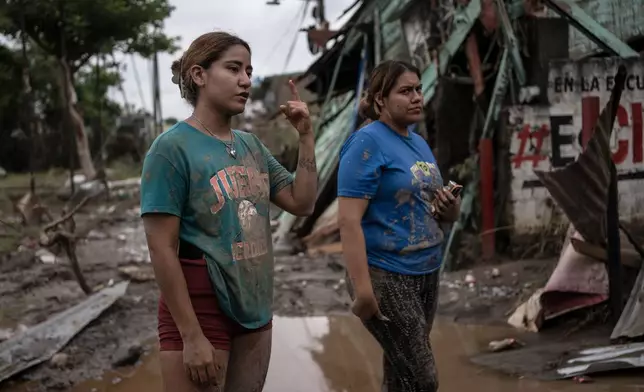 Relatives of Gustavo Azuara, who died during a flood, stand outside their damaged house after heavy rainfall in Poza Rica, Veracruz state, Mexico, Saturday, Oct. 11, 2025. (AP Photo/Felix Marquez)