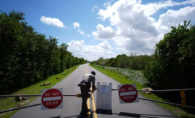 National Park Service law enforcement ranger Greg Freeman opens a locked gate closing vehicle access to the Shark Valley section of Florida's Everglades National Park, as he drives into the park, Wednesday, Oct. 1, 2025. (AP Photo/Rebecca Blackwell)