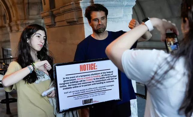 People take photos with a sign announcing that the Library of Congress is closed, on the first day of a partial government shutdown, Wednesday, Oct. 1, 2025, in Washington. (AP Photo/Julia Demaree Nikhinson)