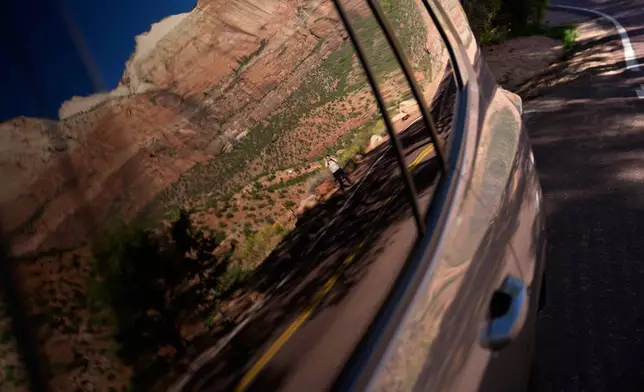 A person is reflected in a window while visiting Zion National Park, Wednesday, Oct. 1, 2025, near Springdale, Utah. (AP Photo/John Locher)