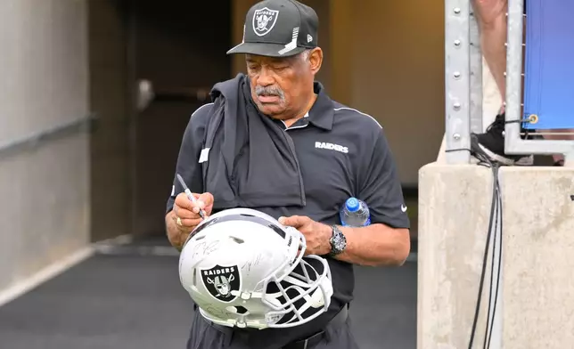 FILE - Former Oakland Raiders safety George Atkinson signs his autograph before the NFL football exhibition Hall of Fame Game between the Las Vegas Raiders and the Jacksonville Jaguars, Aug. 4, 2022, in Canton, Ohio. (AP Photo/David Richard, file)