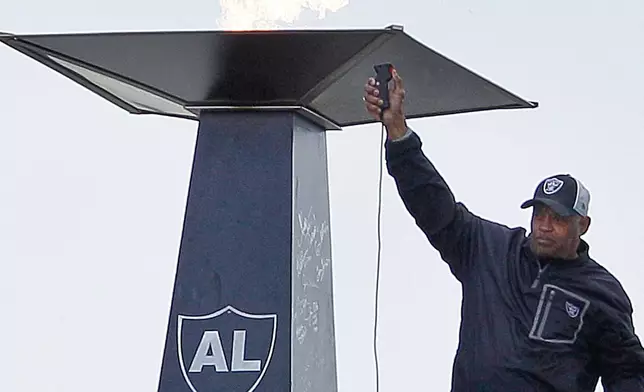 FILE - Former Oakland Raiders player George Atkinson waves after lighting a torch for former Raiders owner Al Davis before an NFL football game between the Oakland Raiders and the Jacksonville Jaguars in Oakland, Calif., Oct. 21, 2012. (AP Photo/Jeff Chiu, file)