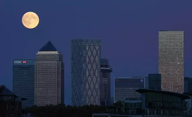 The Harvest Supermoon rises above Canary Wharf, in London, Monday, Oct. 6, 2025. (AP Photo/Kin Cheung)