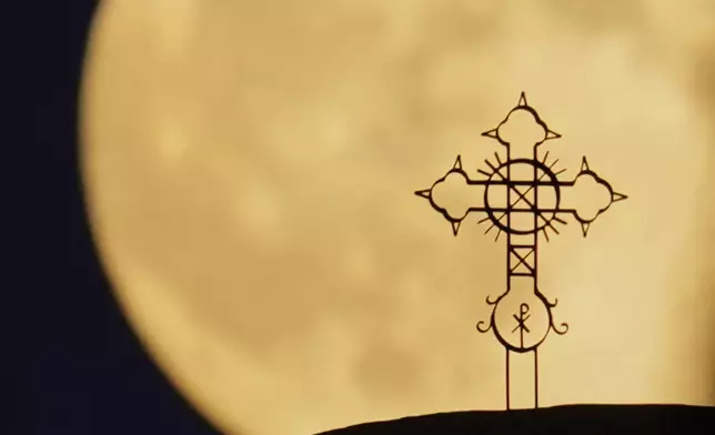 The Harvest Supermoon rises behind the cross of 'Metamorphosis Sotiros' Christian Orthodox Church at Anthoupolis outskirts of capital Nicosia, Cyprus, on Monday, Oct, 6, 2025. (AP Photo/Petros Karadjias)
