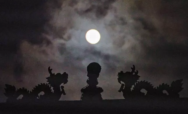 The Harvest Supermoon rises over the Thien Tau Temple in Chinatown Los Angeles Monday, Oct. 6, 2025. (AP Photo/Damian Dovarganes)