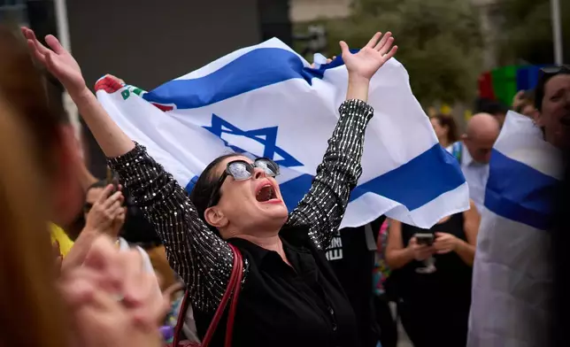 People react as they celebrate following the announcement that Israel and Hamas have agreed to the first phase of a peace plan to pause the fighting, at a plaza known as hostages square in Tel Aviv, Israel, Thursday, Oct. 9, 2025. (AP Photo/Emilio Morenatti)