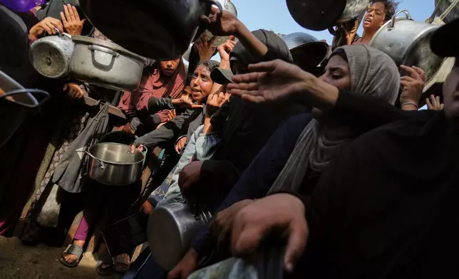 Palestinians struggle to get donated food at a community kitchen in Khan Younis, southern Gaza Strip, Sunday, Oct. 5, 2025. (AP Photo/Jehad Alshrafi)