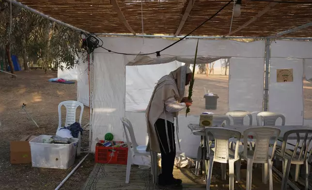 A Jewish man prays during the holiday of Sukkot in an area near the Israeli-Gaza border, in the southern Israel, Thursday, Oct. 9, 2025, after the announcement that Israel and Hamas have agreed to the first phase of a peace plan to pause fighting and release at least some hostages and prisoners. (AP Photo/Ariel Schalit)