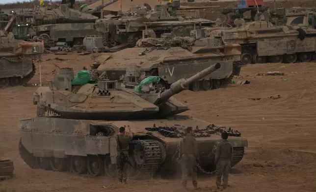 Israeli soldiers work on a tank near the Israeli-Gaza border, as seen from southern Israel, Thursday, Oct. 9, 2025, following the announcement that Israel and Hamas have agreed to the first phase of a peace plan to pause the fighting. (AP Photo/Ariel Schalit)