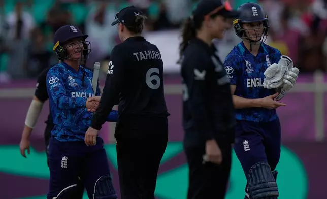 England's Daniel Wyatt-Hodge, left, Amy Jones, extreme right, shake hands with New Zealand's players after winning the ICC Women's Cricket World Cup match against New Zealand at ACA–VDCA Cricket Stadium in Visakhapatnam, India, Sunday, Oct. 26, 2025. (AP Photo/Mahesh Kumar A.)