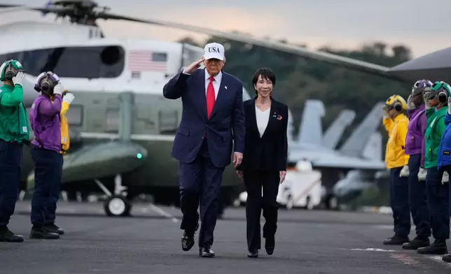 President Donald Trump and Japanese Prime Minister Sanae Takaichi walk on the USS George Washington, an aircraft carrier docked at a U.S. naval base, before speaking to members of the military, in Yokosuka, south of Tokyo, Tuesday, Oct. 28, 2025. (AP Photo/Mark Schiefelbein)