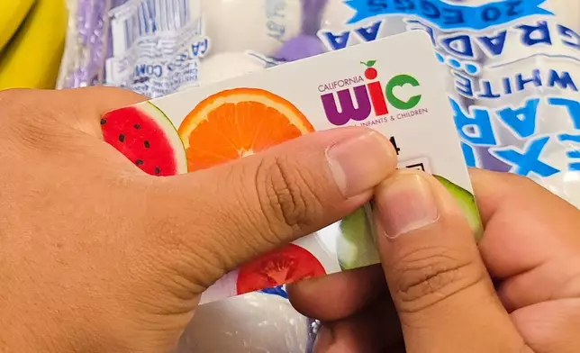 A shopper shows their WIC card on Monday, Oct. 27, 2025, in Los Angeles. (AP Photo/Damian Dovarganes)