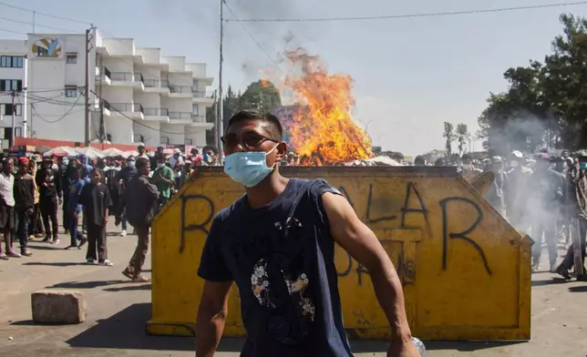 An protester watches police near burning barricades during a protest calling for the president to step down in Antananarivo, Madagascar, Thursday, Oct. 9, 2025. (AP Photo/Alexander Joe)