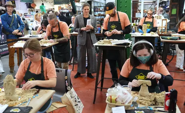 The chief executive of the Philadelphia Museum of Art, Sasha Suda, center top, walks amongst competitors in the Scrapple Sculpting Contest at the Reading Terminal Market in Philadelphia, Friday, Oct. 10, 2025. (AP Photo/Matt Rourke)