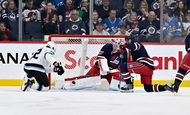 Winnipeg Jets goaltender Connor Hellebuyck (37) makes a save against Utah Mammoth Jack McBain (22) during the second period of an NHL hockey game in Winnipeg, Manitoba, Sunday, Oct. 26, 2025. (Fred Greenslade/The Canadian Press via AP)