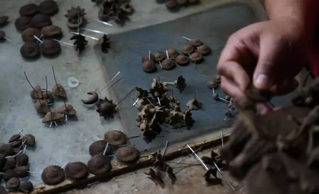 Mexican craftsman Luis Hernandez inserts small fragile clay figures into a tree of life sculpture at his atelier in Metepec, Mexico, Thursday, Oct. 9, 2025. (AP Photo/Fernando Llano)