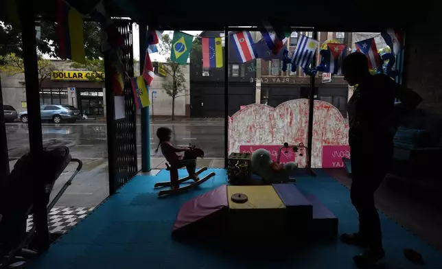 A girl rides a rocking horse as her grandmother looks o inside Luna y Cielo Play Cafe in Chicago's Logan Square neighborhood, Wednesday, Oct. 15, 2025. (AP Photo/Rebecca Blackwell)