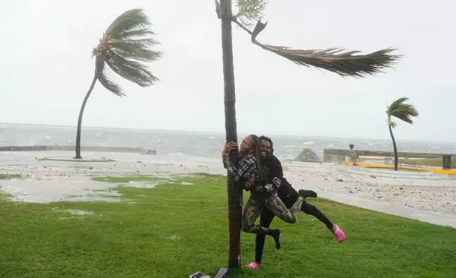 A couple jokes around on the coast in Kingston, Jamaica, as Hurricane Melissa approaches, Tuesday, Oct. 28, 2025. (AP Photo/Matias Delacroix)