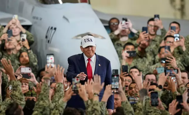 U.S. soldiers wave and take smartphones photos of President Donald Trump as he arrives to the aircraft carrier USS George Washington at the U.S. Navy's Yokosuka base, in Yokosuka, south of Tokyo, Tuesday, Oct. 28, 2025. (AP Photo/Eugene Hoshiko)