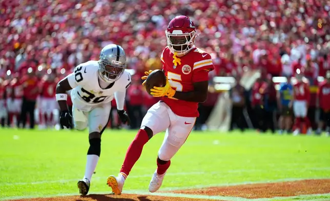 Kansas City Chiefs wide receiver Hollywood Brown (5) scores as Las Vegas Raiders cornerback Darnay Holmes (30) defends during the first half of an NFL football game Sunday, Oct. 19, 2025, in Kansas City, Mo. (AP Photo/Charlie Riedel)
