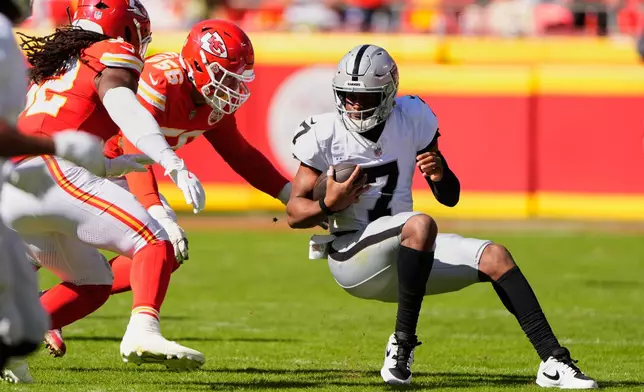 Las Vegas Raiders quarterback Geno Smith (7) scrambles as Kansas City Chiefs defensive end George Karlaftis (56) and linebacker Nick Bolton, left, defend during the first half of an NFL football game Sunday, Oct. 19, 2025, in Kansas City, Mo. (AP Photo/Charlie Riedel)