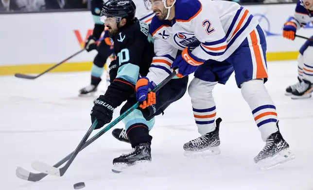 Edmonton Oilers defenseman Evan Bouchard (2) and Seattle Kraken center Matty Beniers (10) collide in the first period of an NHL hockey game Saturday, Oct. 25, 2025, in Seattle. (AP Photo/John Froschauer)