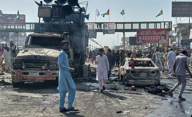 Local residents stand by burnt vehicles after police in Pakistan clashed with thousands of protesters during a march in support of Palestinians, in Muridke near Lahore, Pakistan, Monday, Oct. 13, 2025. (AP Photo/Jahanzeb Khan)