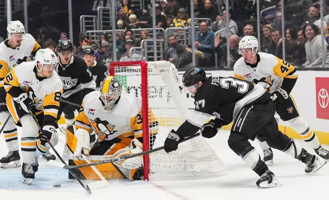 Los Angeles Kings left wing Warren Foegele (37) attempts a shot under defense by Pittsburgh Penguins defenseman Parker Wotherspoon (28) during the second period of an NHL hockey game Thursday, Oct. 16, 2025, in Los Angeles. (AP Photo/Jae C. Hong)