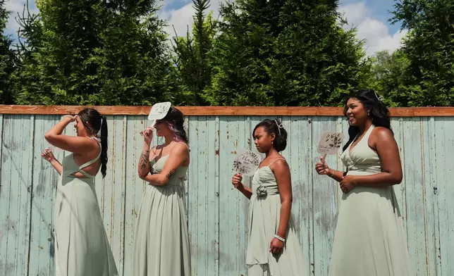 FILE - Bridesmaids use fans for shade and to keep cool during bridal pictures before a wedding Saturday, Aug. 23, 2025, in Newtown, Ohio. (AP Photo/Joshua A. Bickel, File)