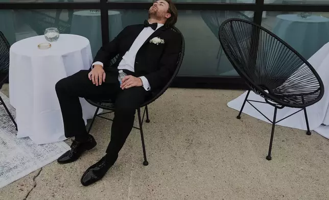 FILE - A Groomsman takes a break after finishing bridal party photos at a wedding on Saturday, Aug. 23, 2025, in Newtown, Ohio. (AP Photo/Joshua A. Bickel, File)
