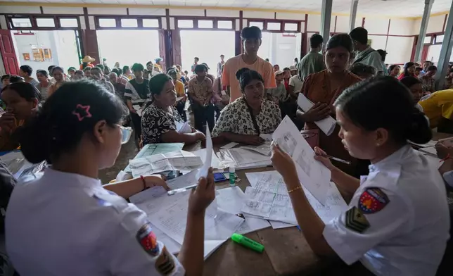 In this photo taken during a trip supervised by pro-military Myanmar media, immigration officers check personal data of locals for lost and damaged national registration cards, at a temporary office in Kyaukme, northern Shan State, Myanmar, Friday, Oct. 10, 2025. (AP Photo/Aung Shine Oo)