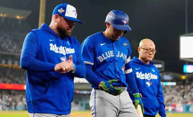Toronto Blue Jays' George Springer, center, walks off the field as he leaves with an injury with manager John Schneider, left, and first assistant athletic trainer Voon Chong, right, during the seventh inning in Game 3 of baseball's World Series against the Los Angeles Dodgers in Los Angeles, Monday, Oct. 27, 2025. (Frank Gunn/The Canadian Press via AP)