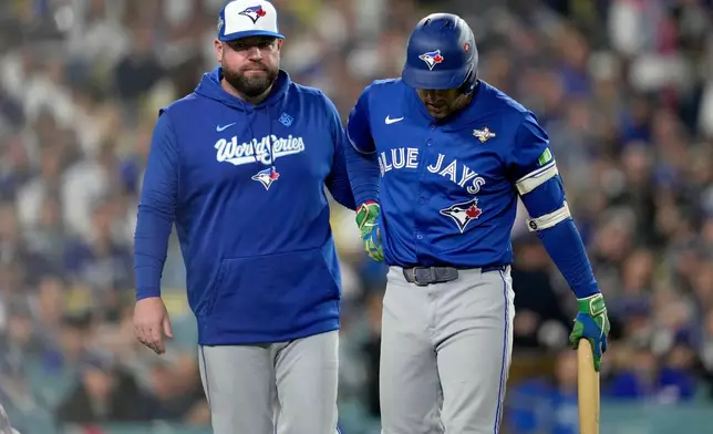 Toronto Blue Jays manager John Schneider helps George Springer off the field with an injury during the seventh inning in Game 3 of baseball's World Series against the Los Angeles Dodgers, Monday, Oct. 27, 2025, in Los Angeles. (AP Photo/Ashley Landis)